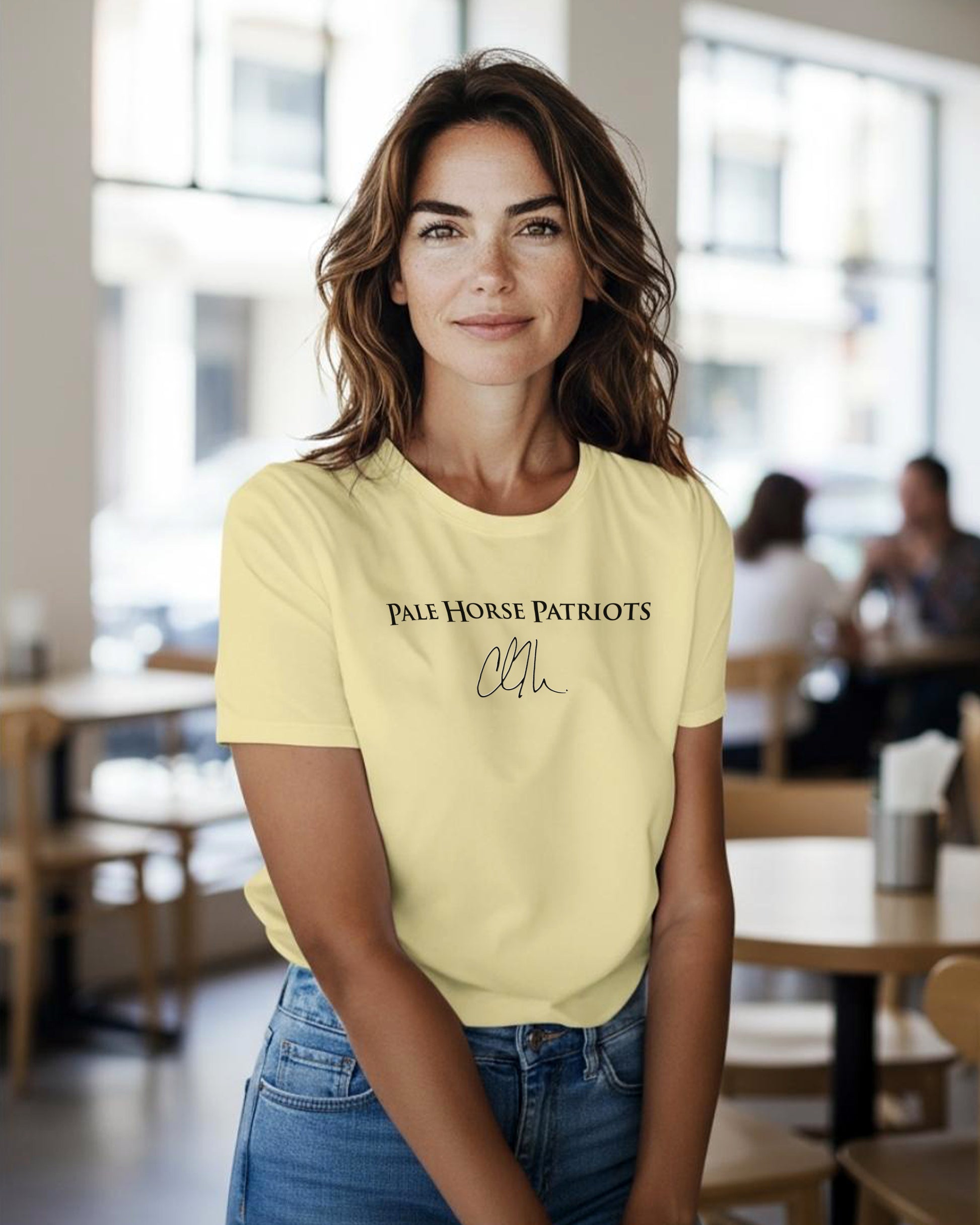 Woman wearing a yellow t-shirt with pale horse patriot logo and charlie kirk signature in a casual setting